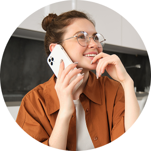 Uśmiechnięta kobieta w okularach rozmawia przez telefon komórkowy.