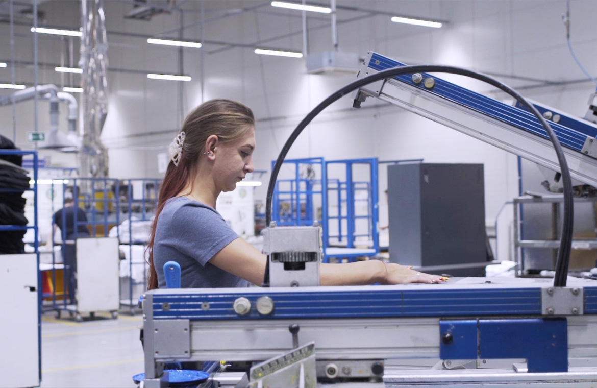 Pracownica Lynka obsługuje maszynę do sitodruku automatycznego na hali produkcyjnej.